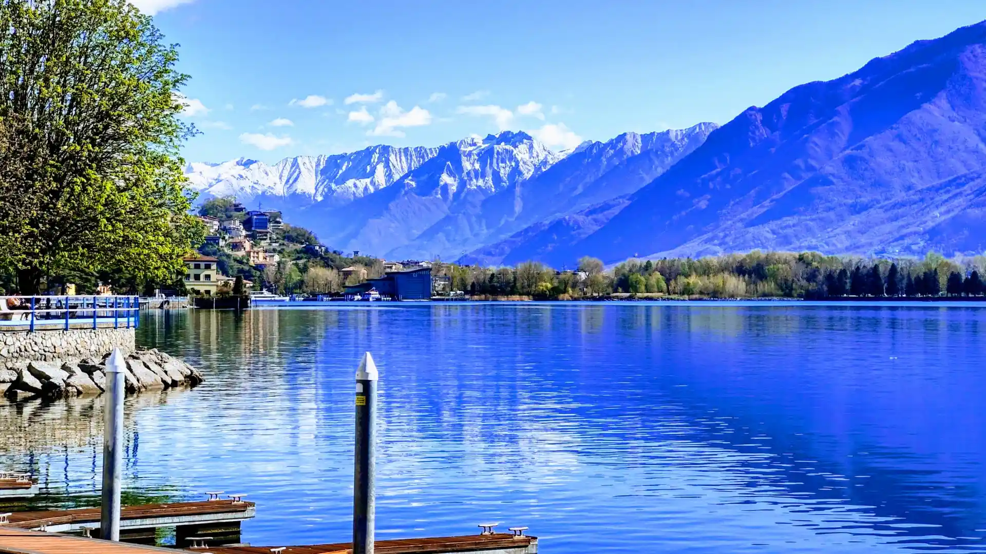 A wharf alongside Lago d'Iseo - Lake Iseo - in northern Italy. Clear blue water, mountains soaring in the background, a hint of snow atop them. The overwhelming impression is one of irridescent blue, which might *just* possibly be from an over-zealous filter.